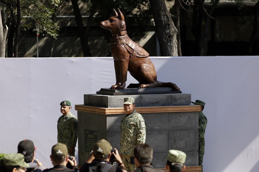 Soldiers stand beside a bronze statue of a rescue dog.