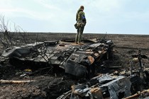 A Ukrainian soldier stands on the wreckage of a Russian tank