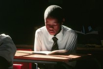 a boy reading a book at a desk
