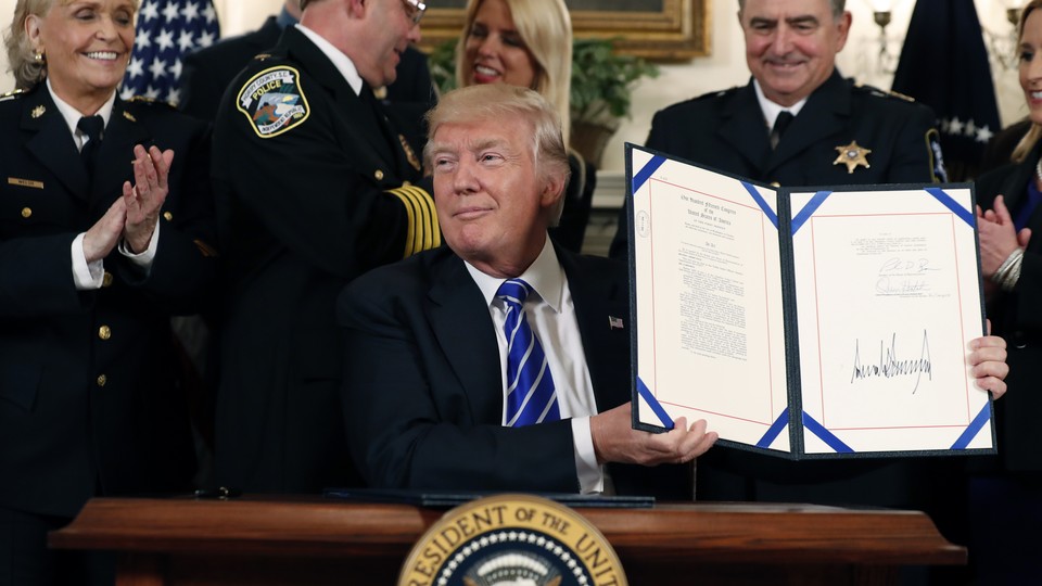President Trump holds a signed bill in at the White House.