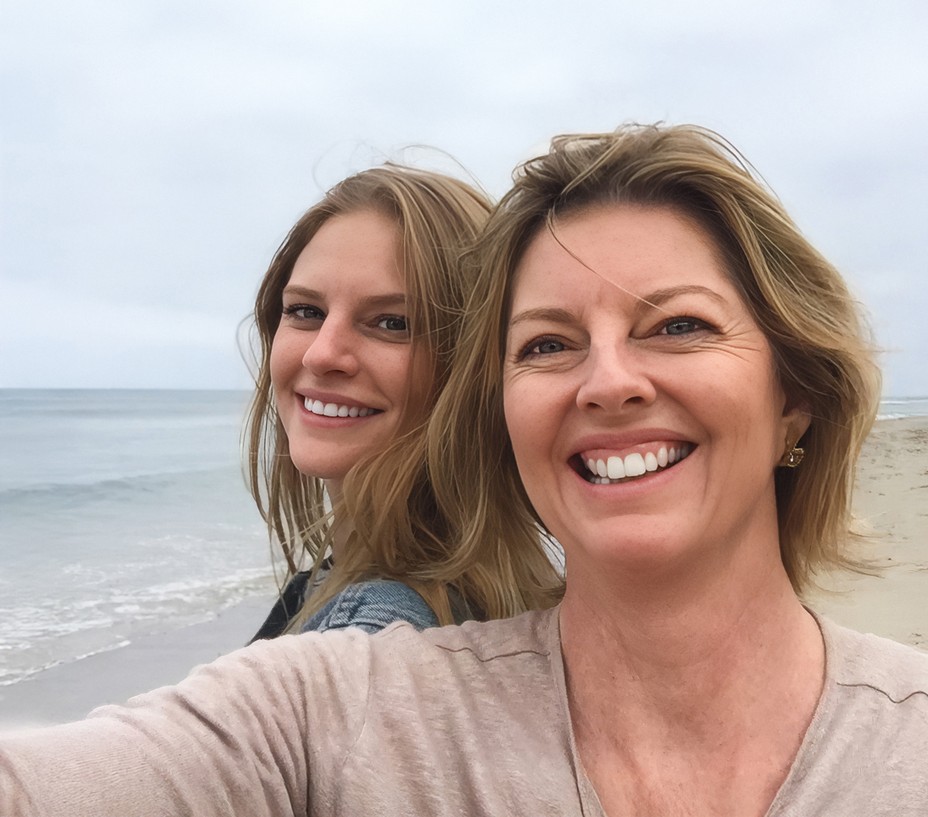 selfie photo of author and her daughter Miranda, smiling on a beach