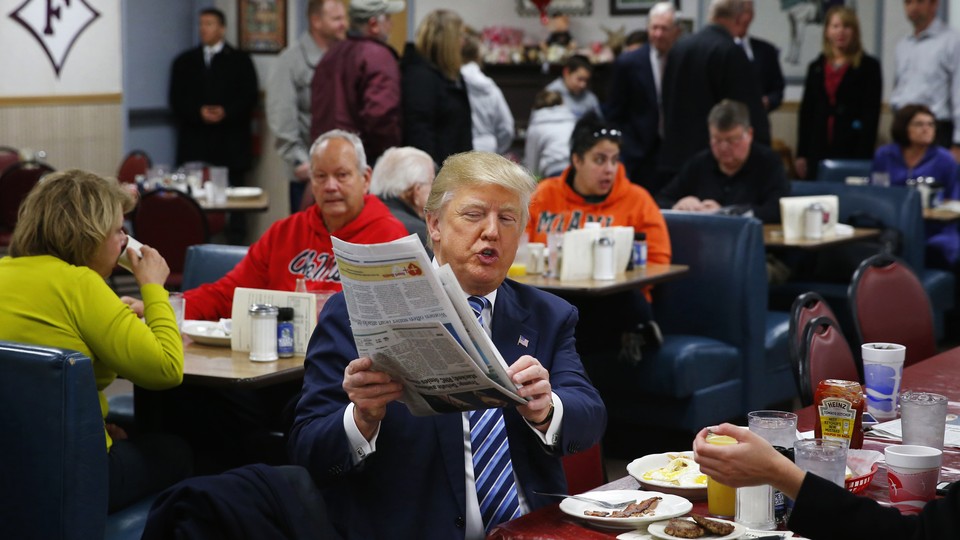 Republican candidate Donald Trump looks at a newspaper 