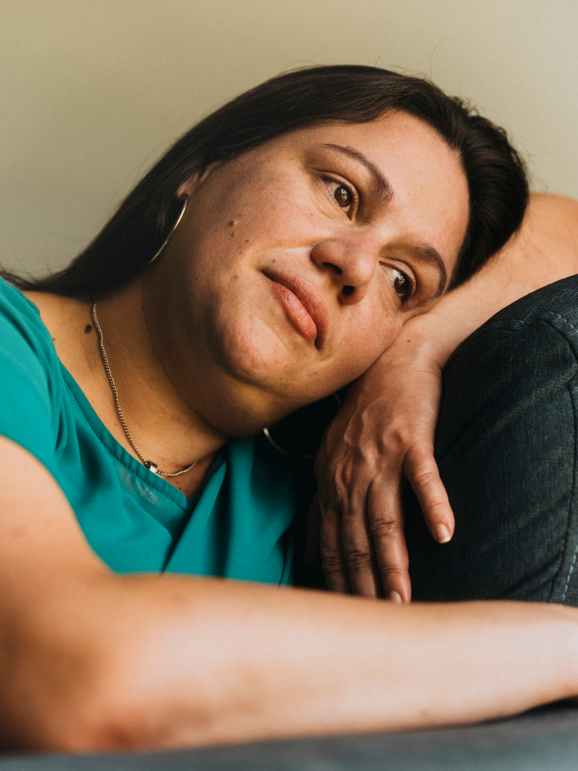 photo of woman with dark hair resting her head on her arm draped across a sofa