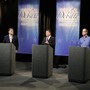 Three senatorial candidates stand at lecterns on a debate stage.