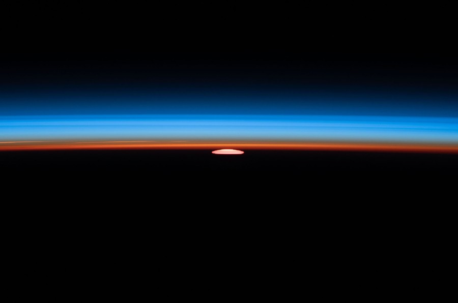 A squashed, red image of the sun is seen right on the horizon.