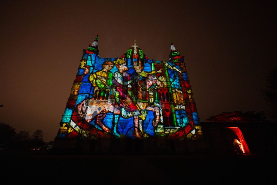 A colorful picture is projected onto the exterior of a cathedral.