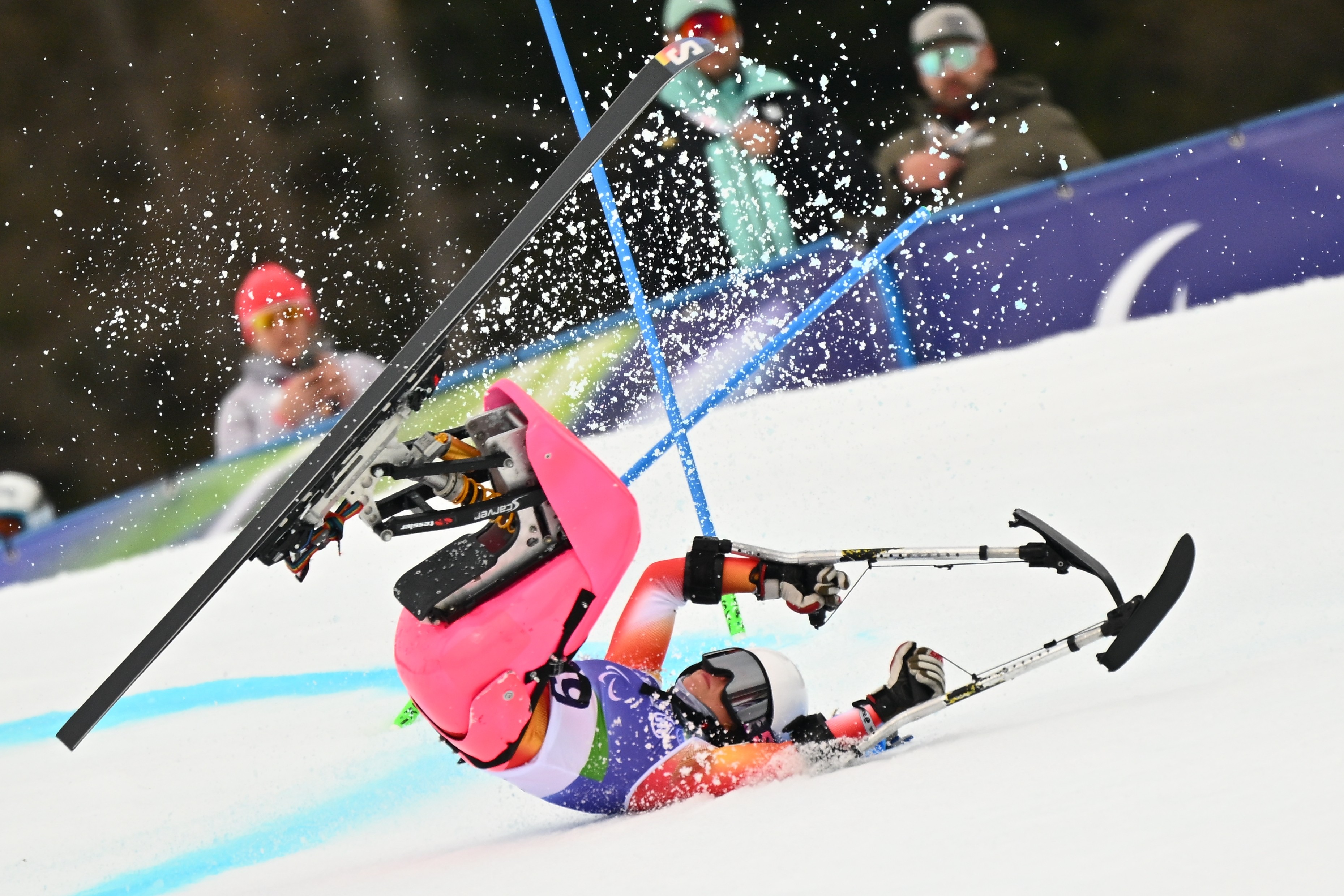 A para-alpine skier sitting on a rapid falls and falls on a ski slope.