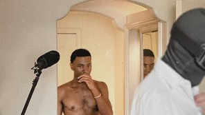 Jerrod Carmichael stands in front of a mirror