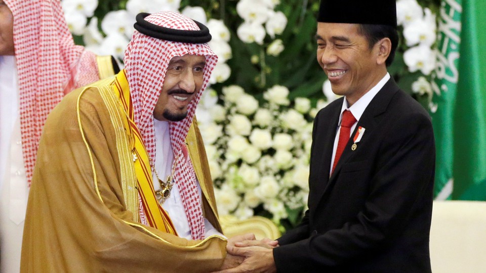 Saudi King Salman shakes hands with Indonesian President Joko Widodo.