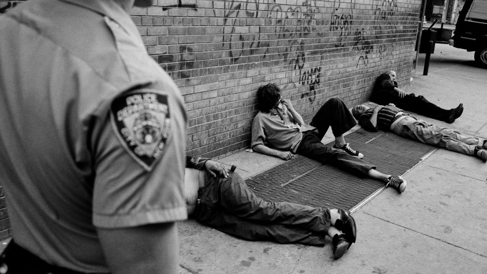 A police officer walking past people lying on the street.