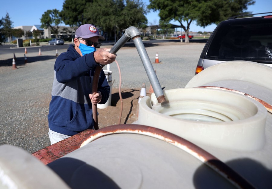 A person fills a large tank on a trailer with water.