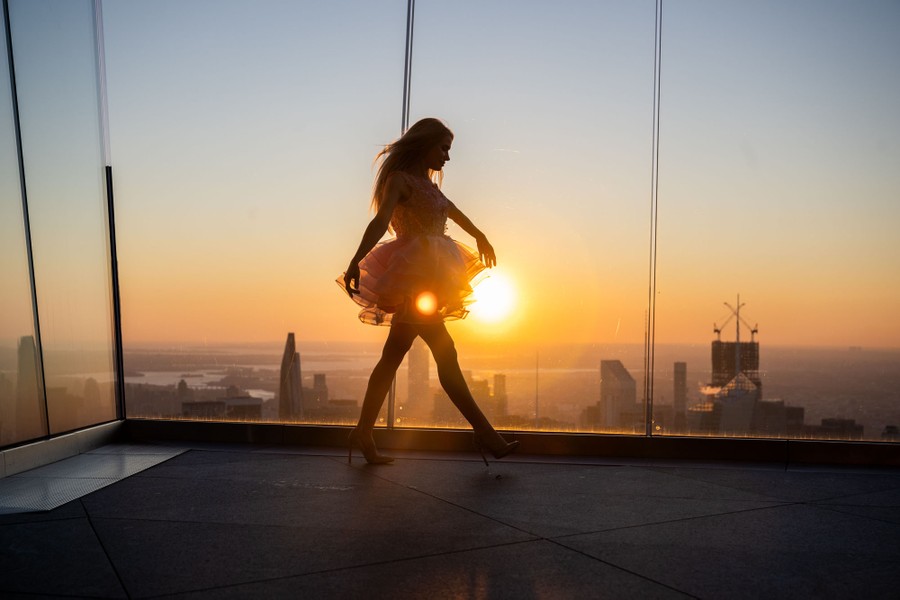 A person poses while walking on a high observation deck at sunrise.