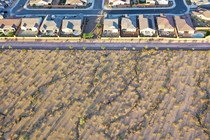 A color aerial photograph of desert landscape abutting a suburban neighborhood