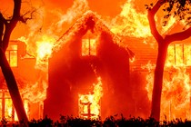 A photo of an entire home set ablaze in a wildfire.