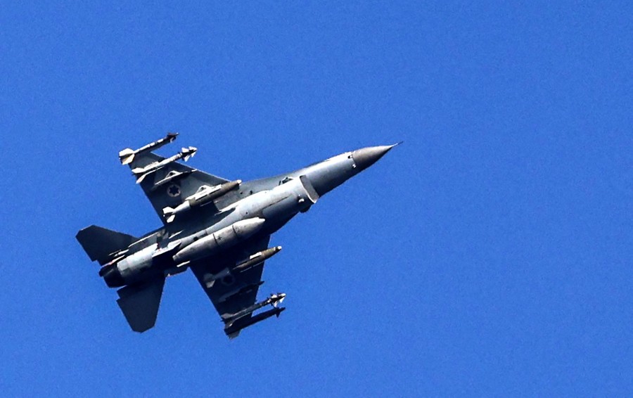 An F16 warplane flies overhead.
