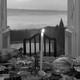 A table set with food and wine and a lit candle, with a door open in the background showing the sky