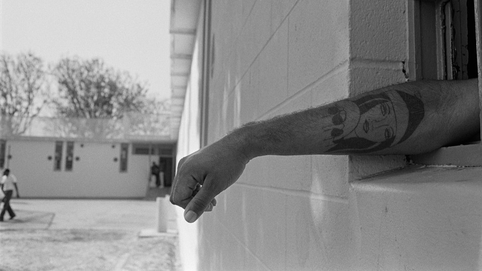 An imprisoned person stretches their arm out of a window.