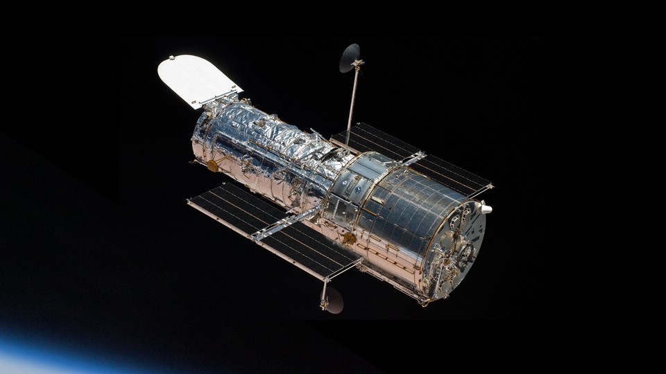 A picture of the Hubble Space Telescope in orbit, shining against the darkness of space