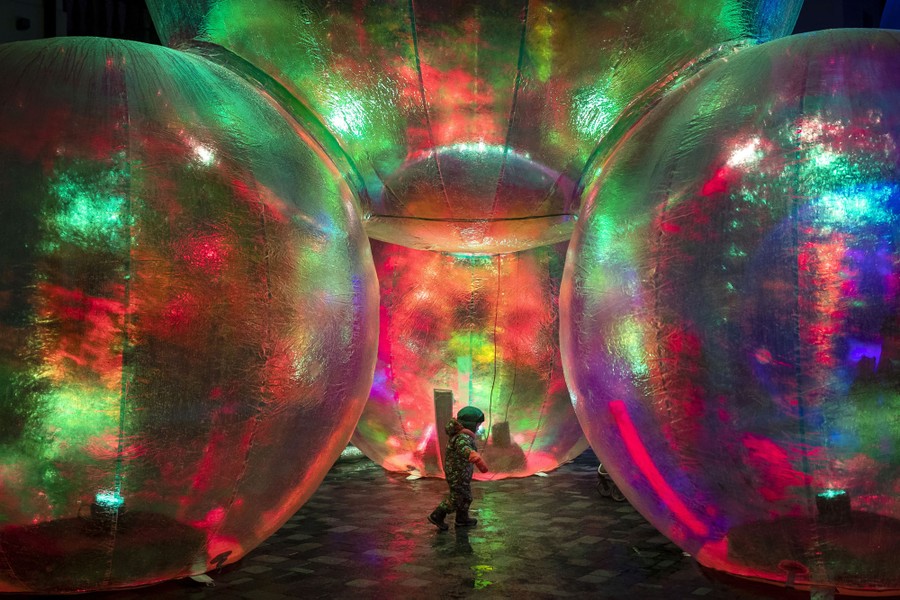 A boy walks among huge illuminated inflated spheres.