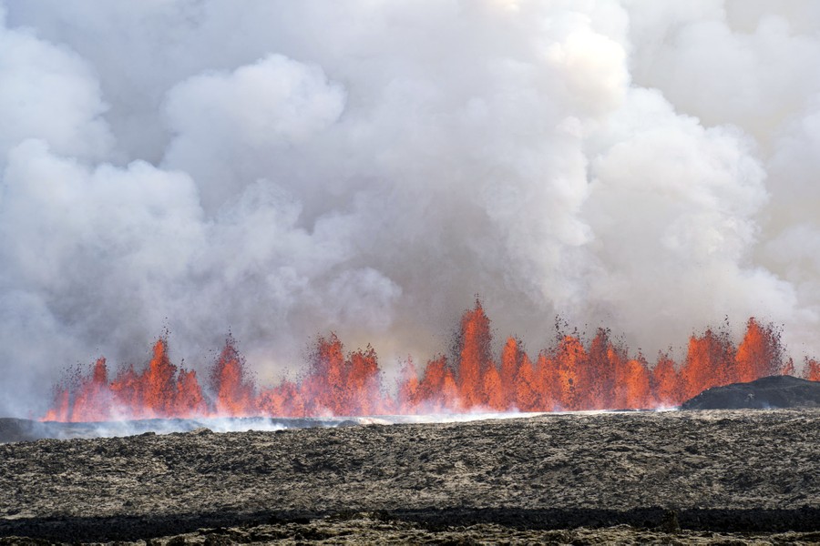 A line of lava fountains erupts from the ground.