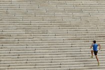 A man in athletic clothing runs up a long flight of stairs