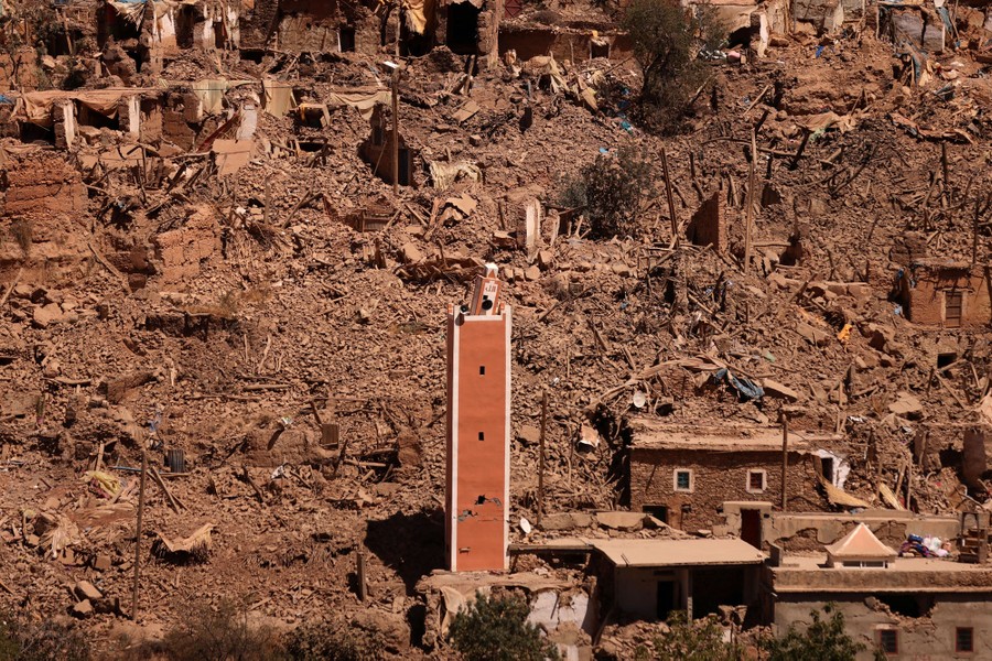 A single damaged tower stands on a hillside, surrounded by the rubble of dozens of smaller buildings, destroyed by an earthquake.