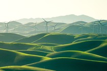 Wind turbines spin over a Elysian landscape of green fields