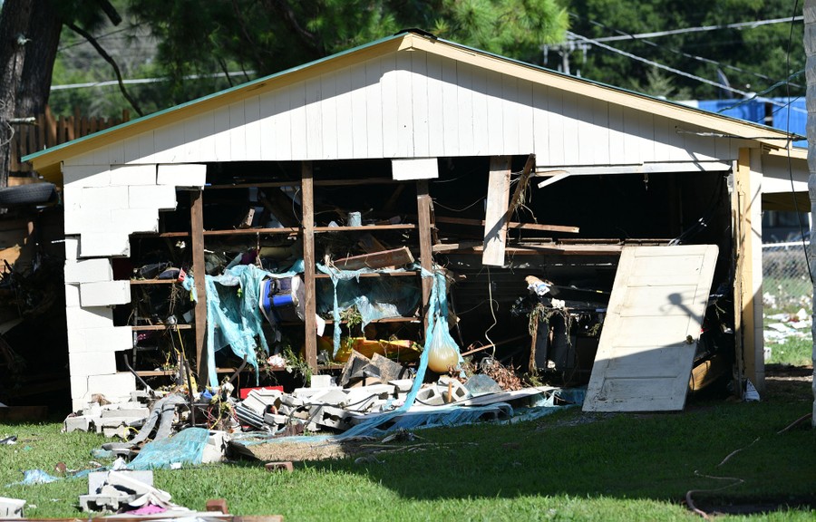 An outer wall of what appears to be a garage has fallen away because of flooding.