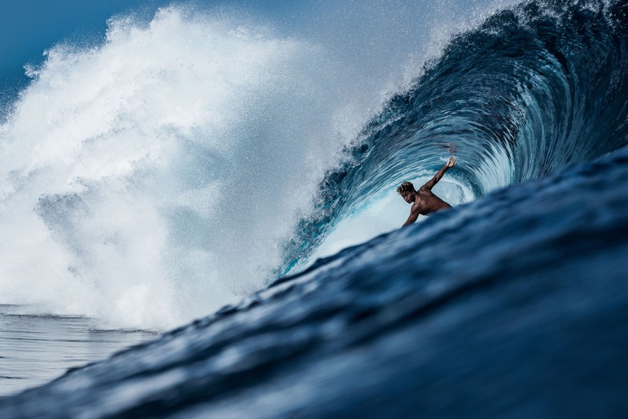 A surfer is seen riding a large wave, inside the curl.