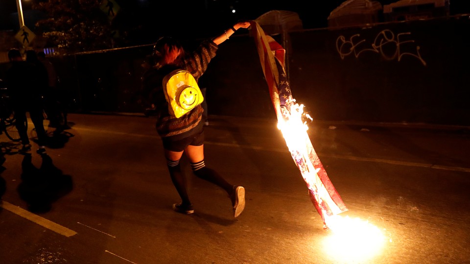 A demonstrator burns an American flag to protest the election of Donald Trump on November 10 in Oakland, Calif.