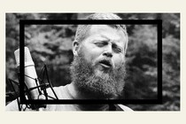 A black-and-white image of Oliver Anthony singing.