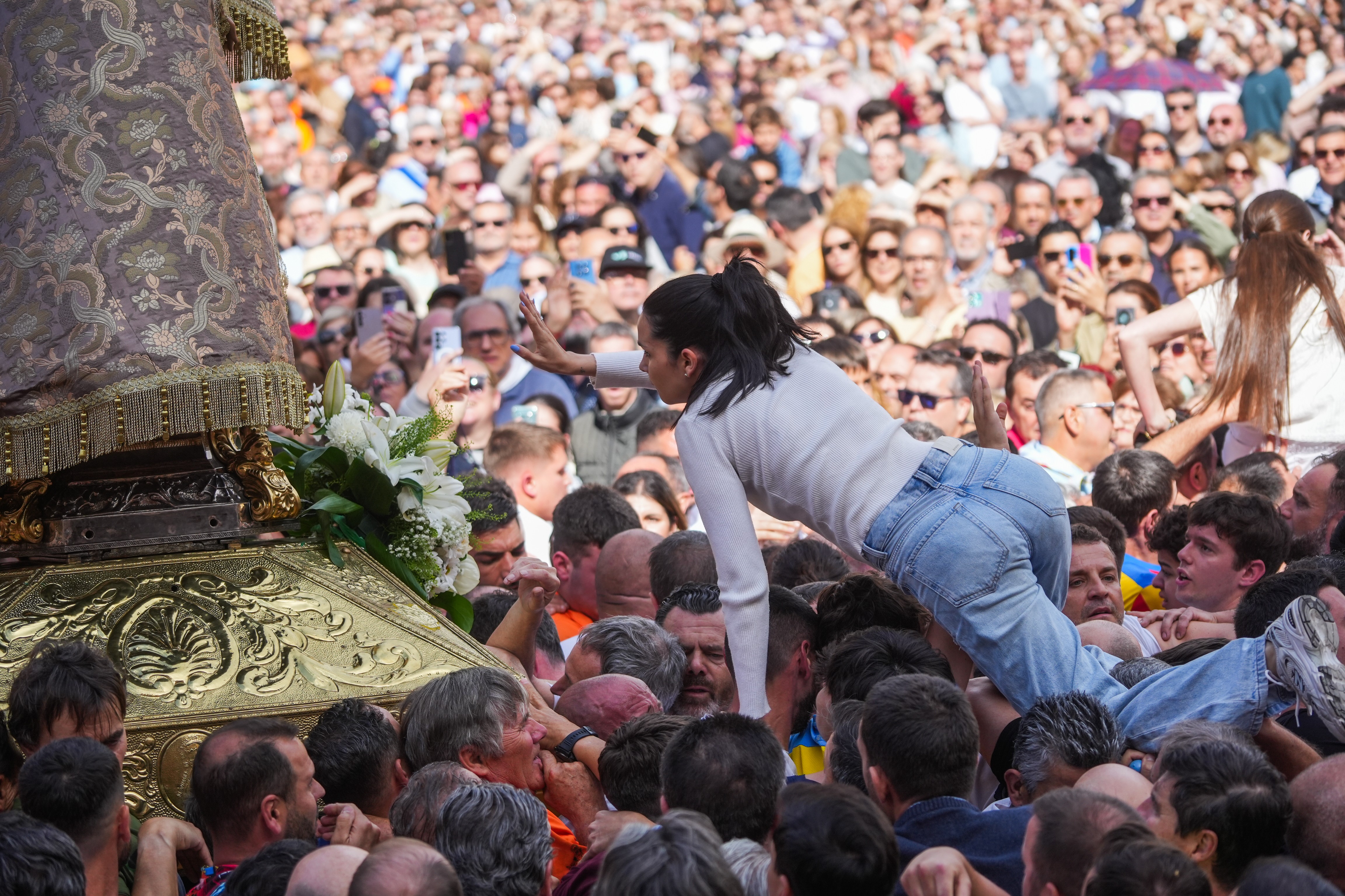 Hundreds of people take part in a religious festival, carrying a statue.