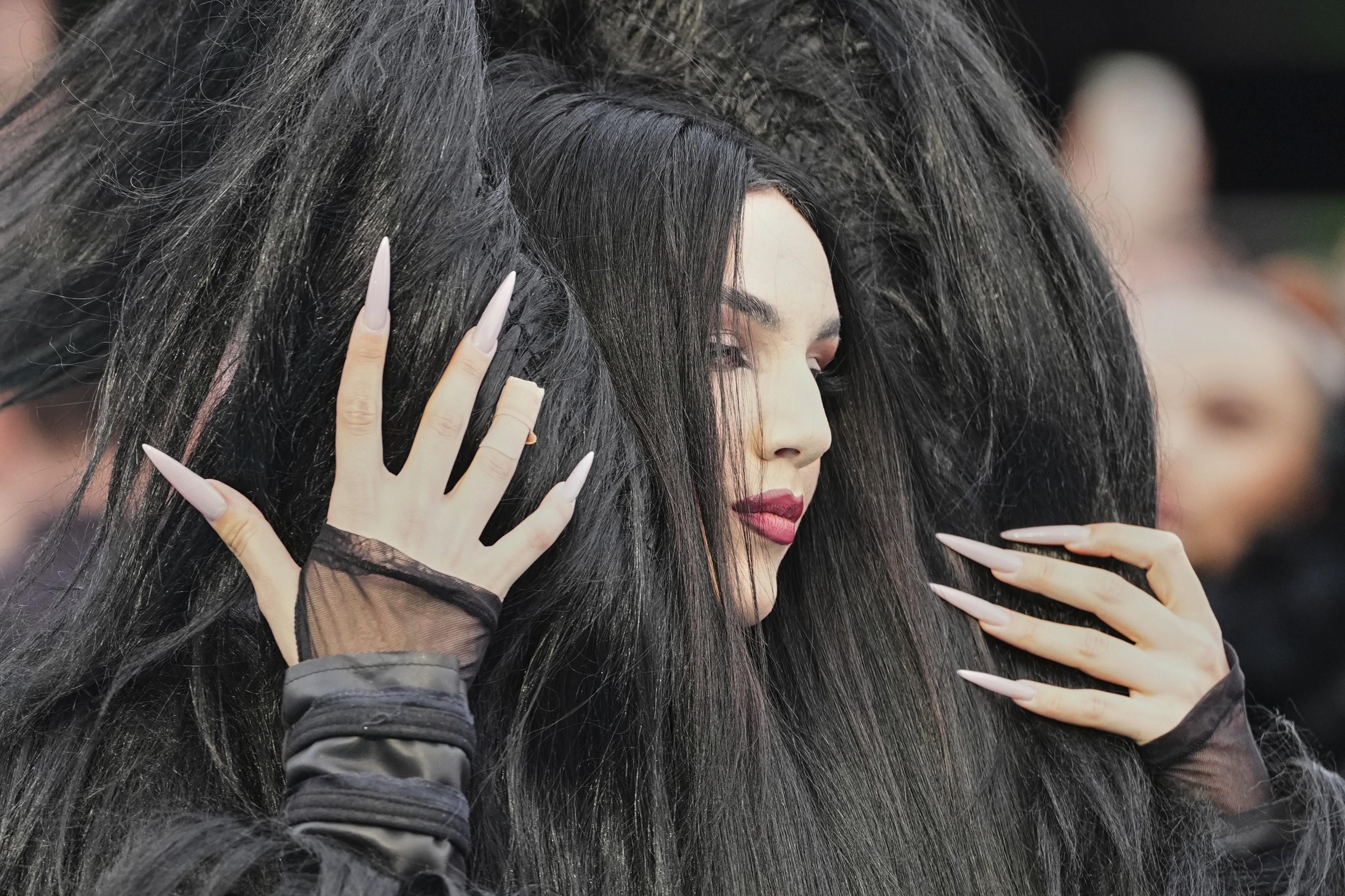 A performer with an elaborate wig poses for photographers.