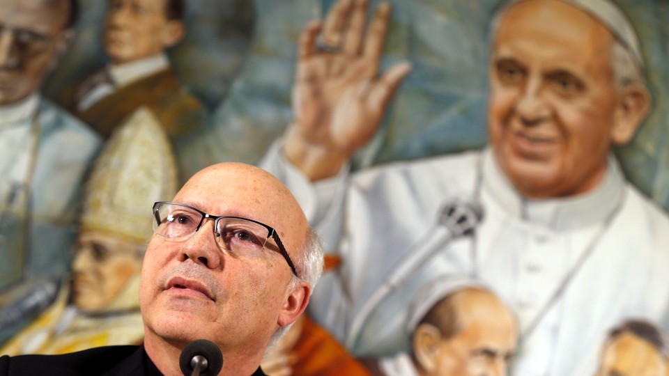 Pérez speaking in front of a mural of Pope Francis