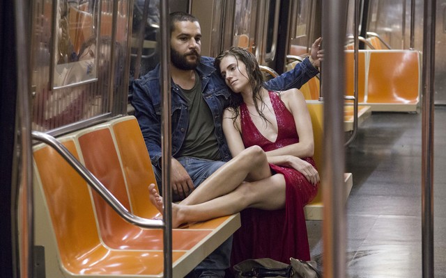 Marnie wears a red dress and leans on Charlie's shoulder in a subway