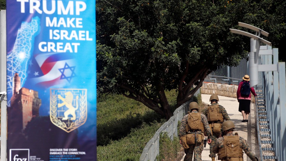 Military personnel patrol next to a sign welcoming the move of the U.S. embassy to Jerusalem.