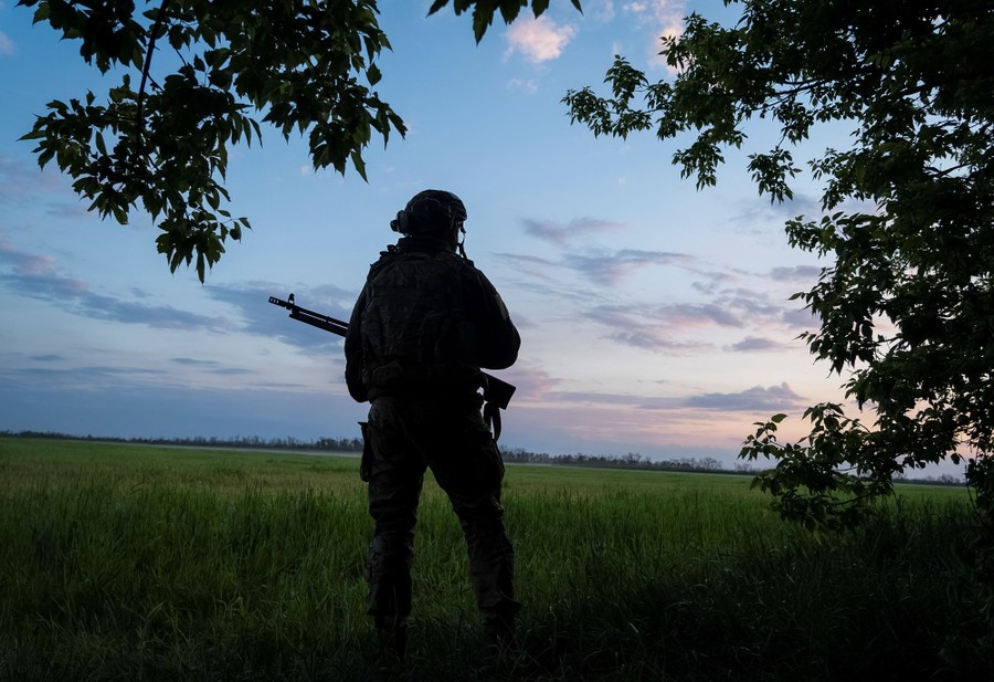 A soldier, seen in silhouette, stands beside a field.