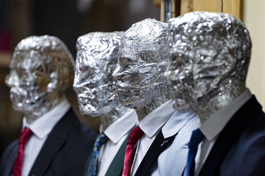 Four mannequins with suits and ties, each with their head covered in aluminum foil