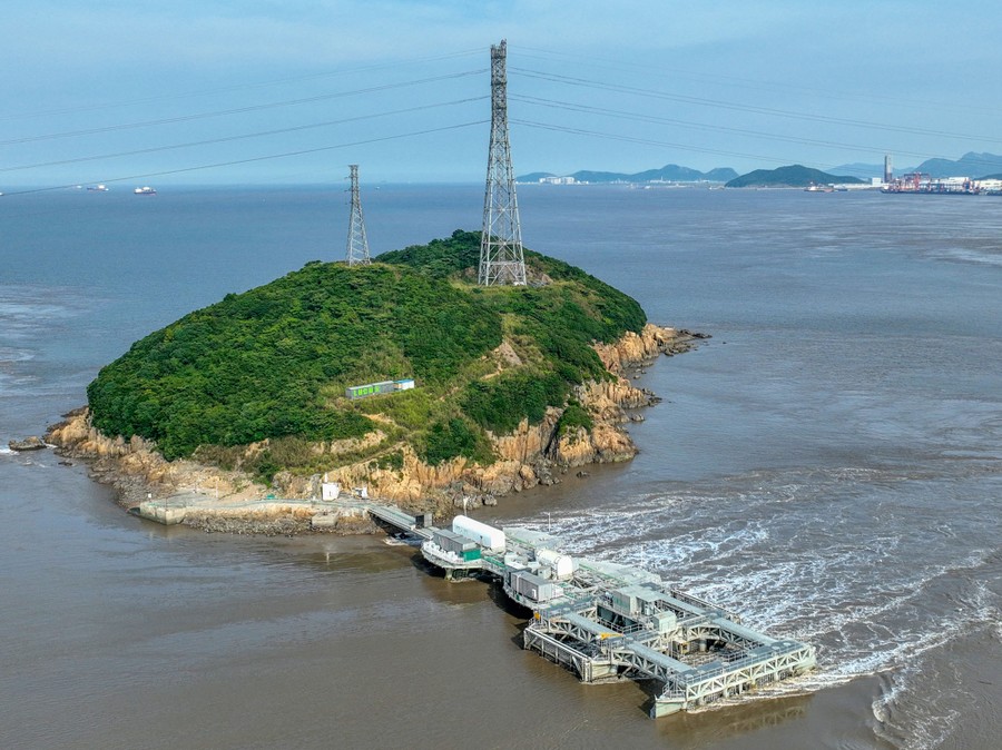 A tidal-current power-generator unit, looking like a complex dock attached to a small island, with tidal waters flowing past quickly