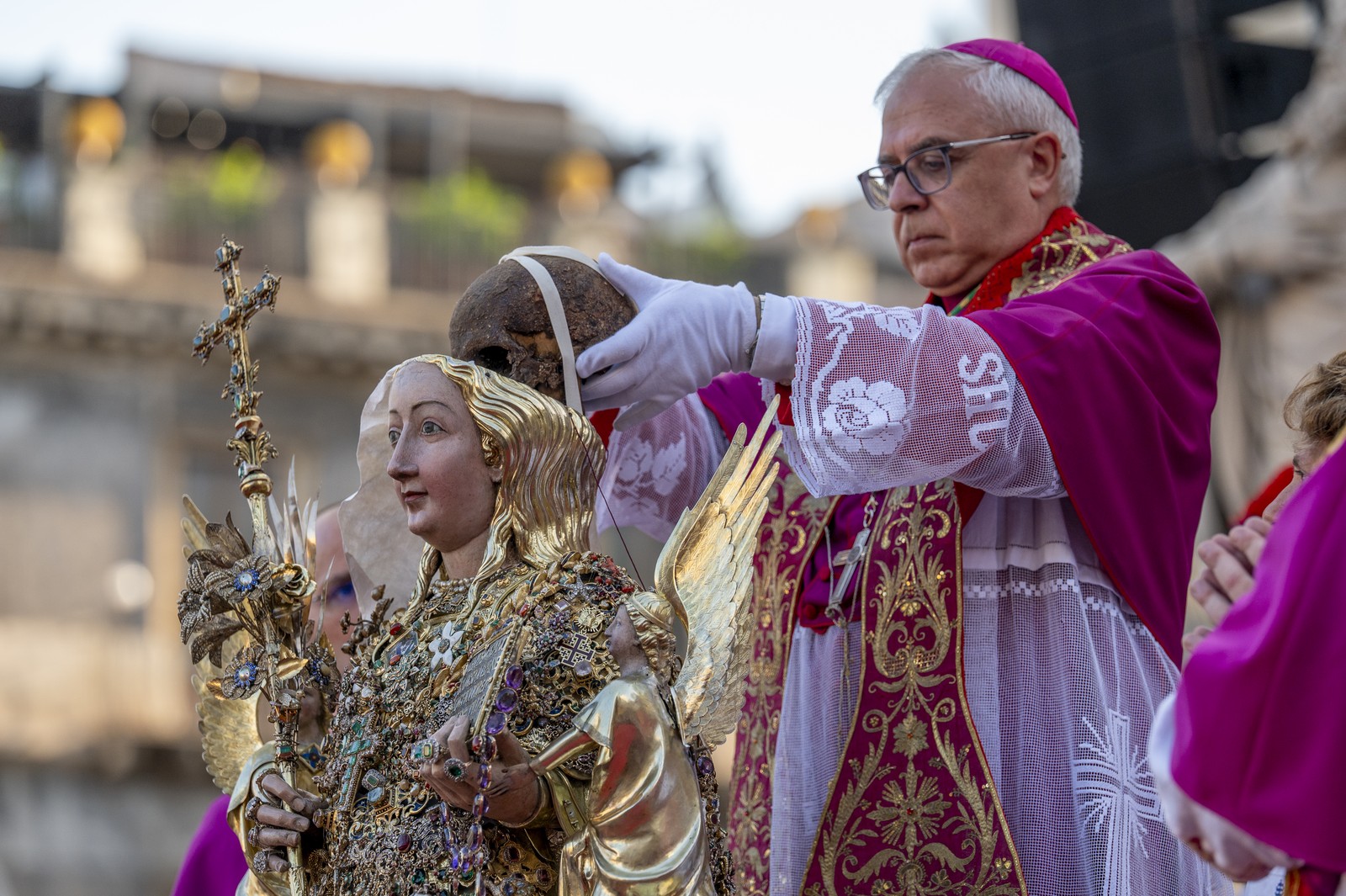 An Archbishop places the skull of a saint inside the head of ornate reliquary bust.