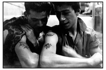 A photo of two young men with tattoos on their arm