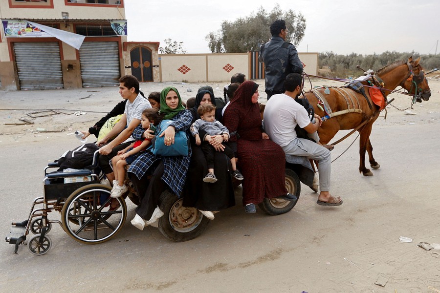 About a dozen men, women, and children ride on a small cart pulled by a horse.