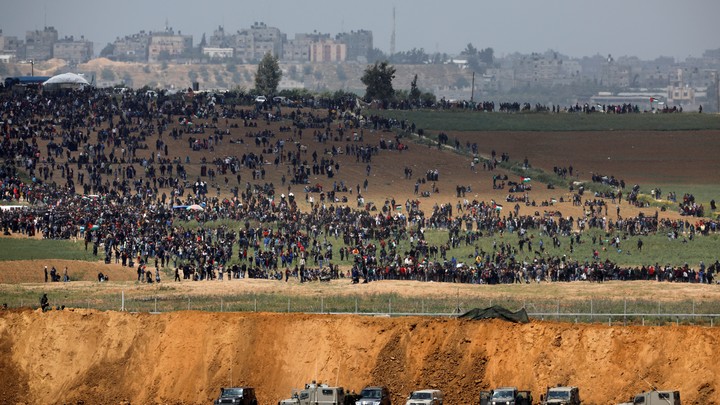 Israeli military vehicles are seen Friday next to the border on the Israeli side of the Israel-Gaza border, as Palestinians demonstrate in Gaza.