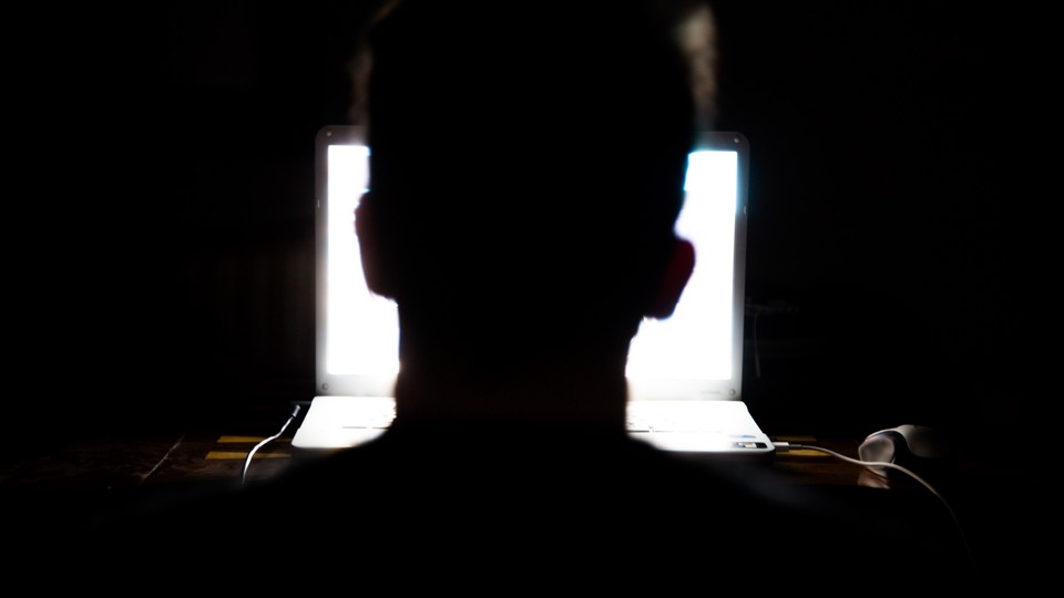 Man sitting in front of a laptop computer in the dark