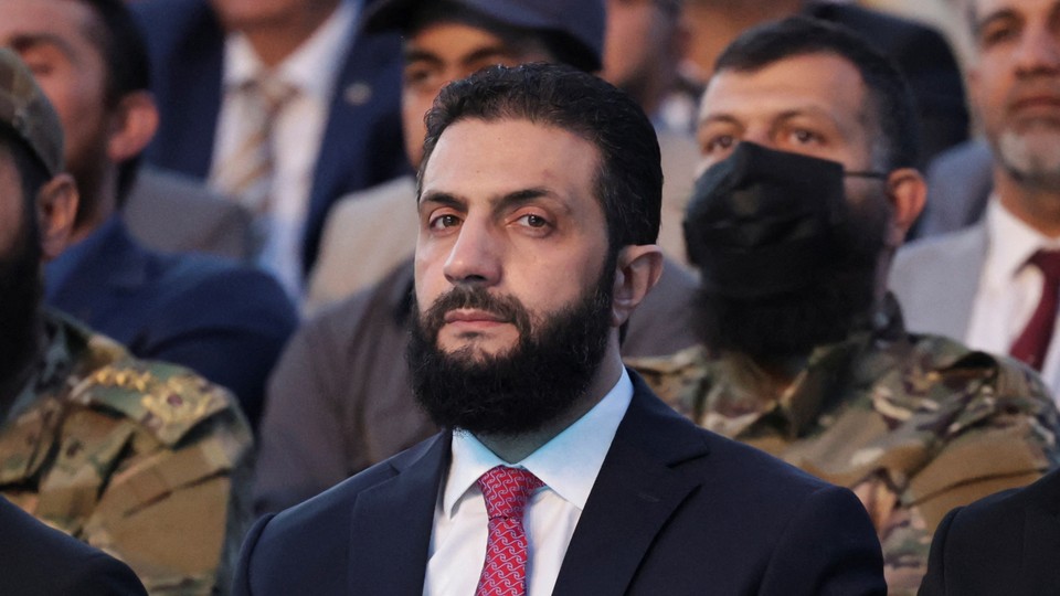 Ahmed al-Sharaa looking at the camera in front of a group of men