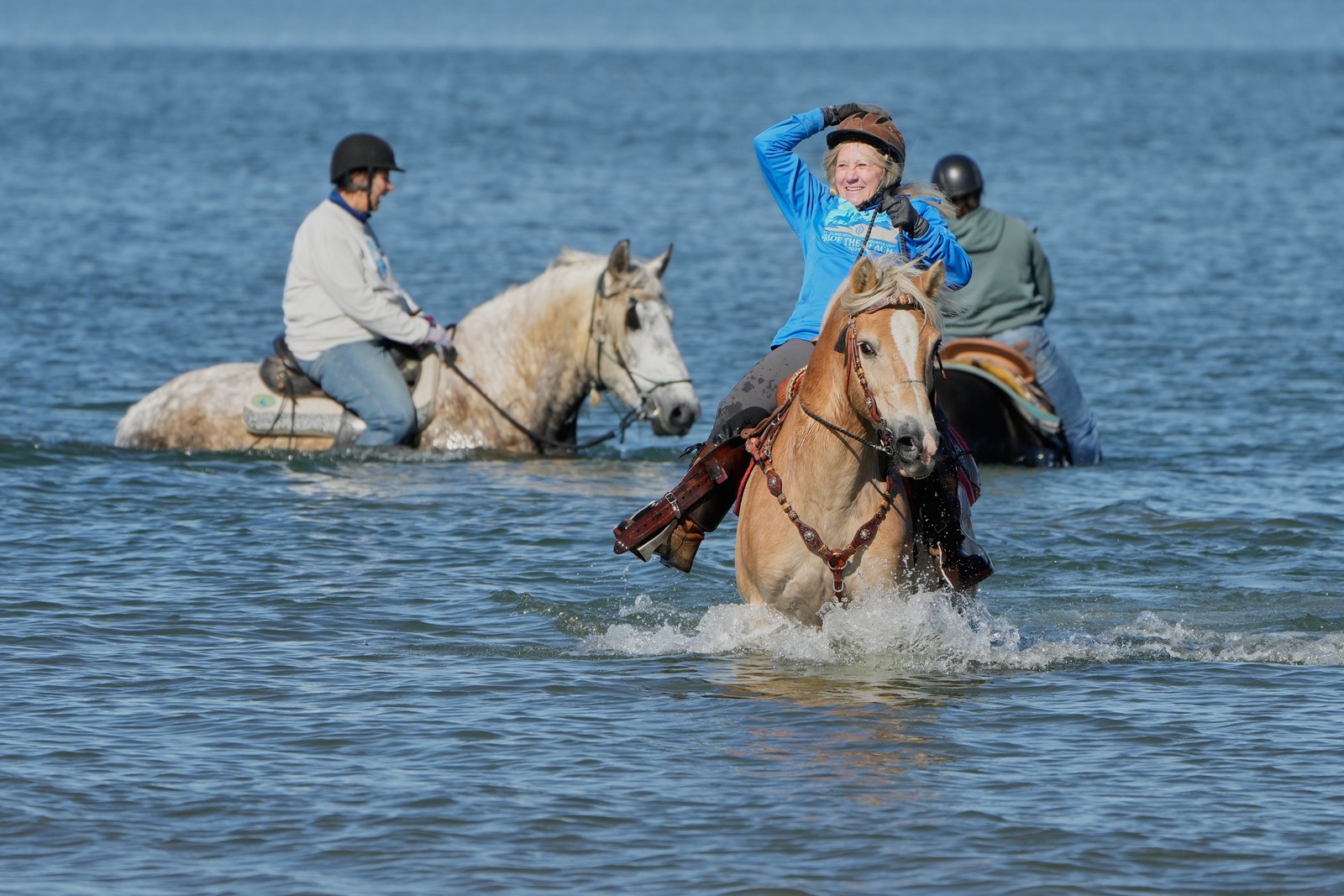 Several people ride horses in shallow water.