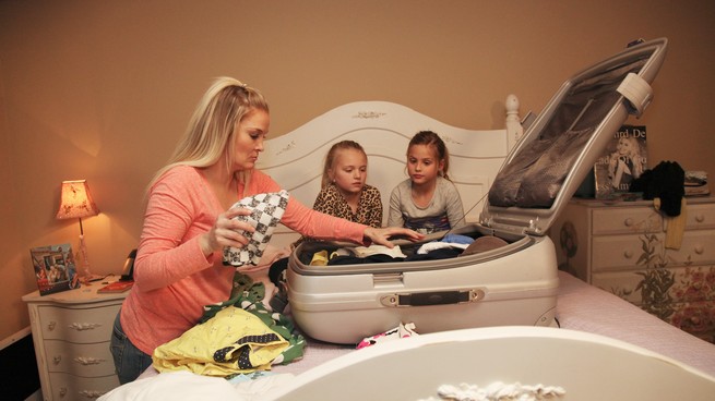 A mother packs a suitcase while children look on in "Celebrity Wife Swap."