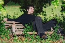 The guitarist MJ Lenderman, sitting on a bench