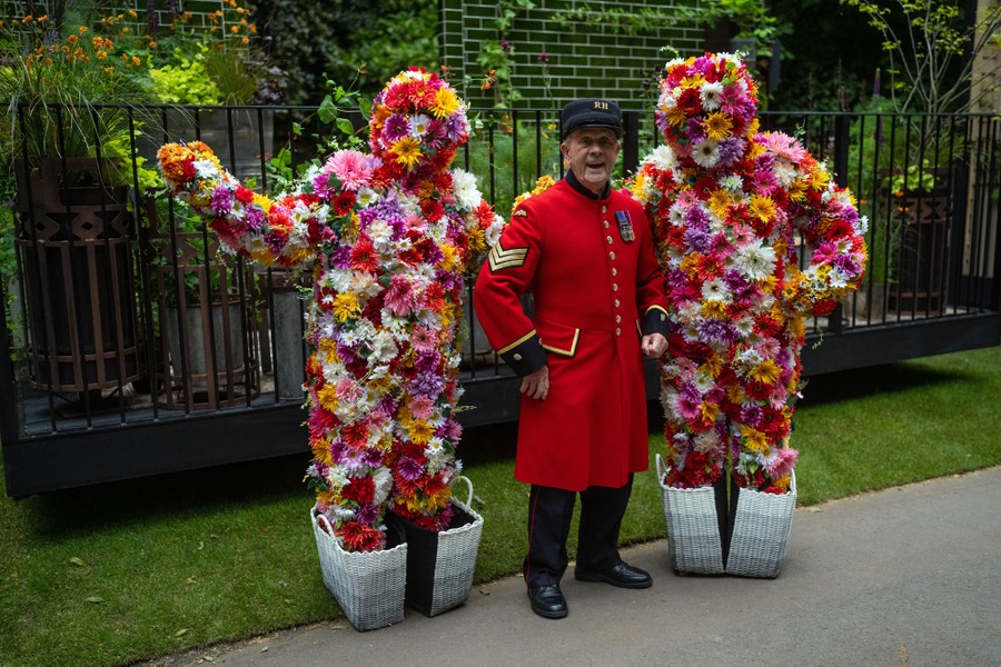 A man in a dress uniform stands between two people in floral costumes.