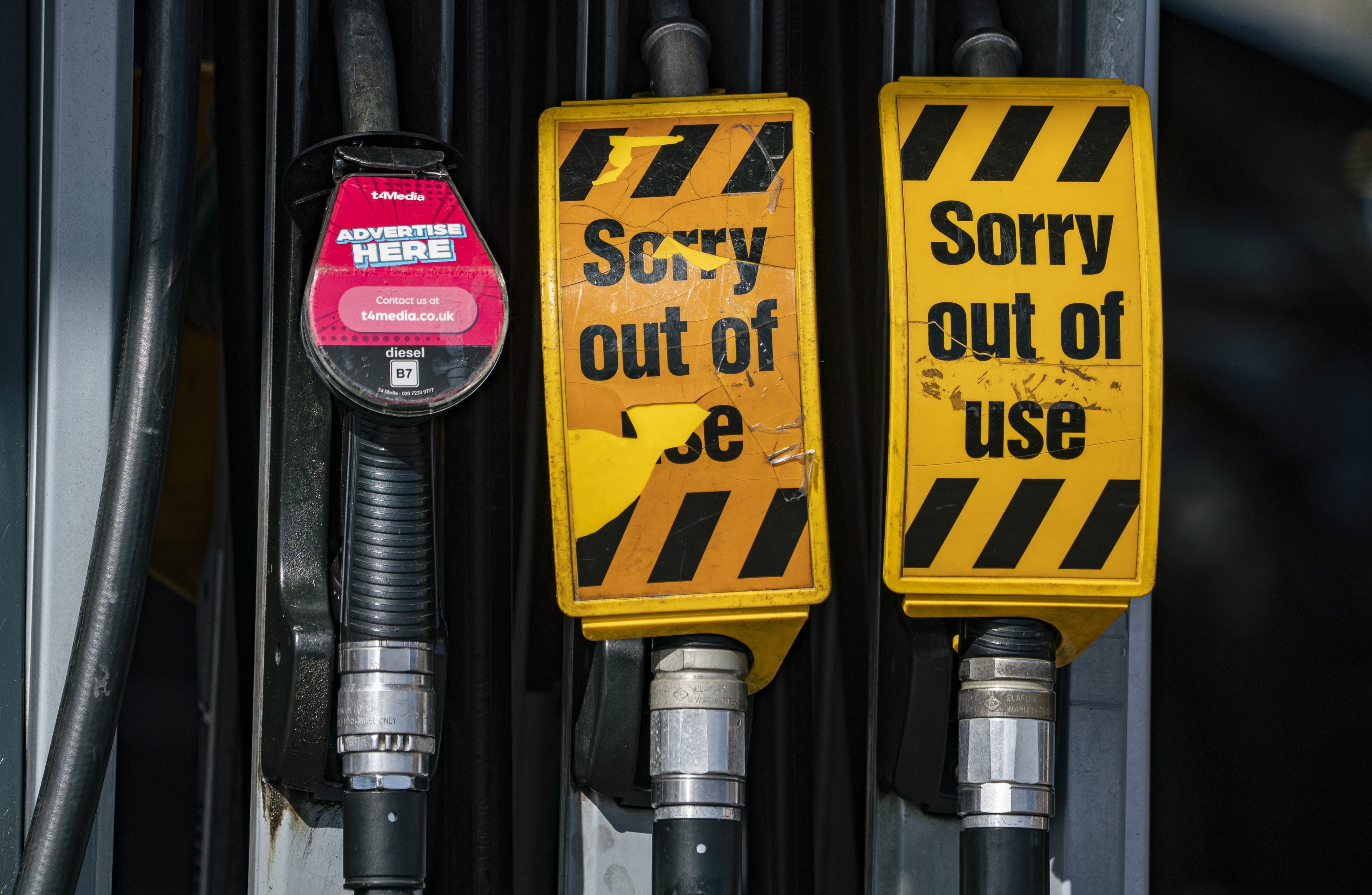 Yellow 'sorry, out of use' signs, placed on unleaded gasoline dispensers.
